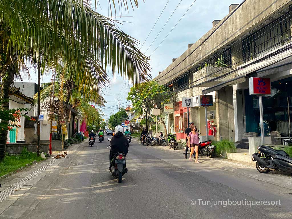 Motorcycles, pedestrians and local businesses sharing a narrow road in Pererenan, Bali.