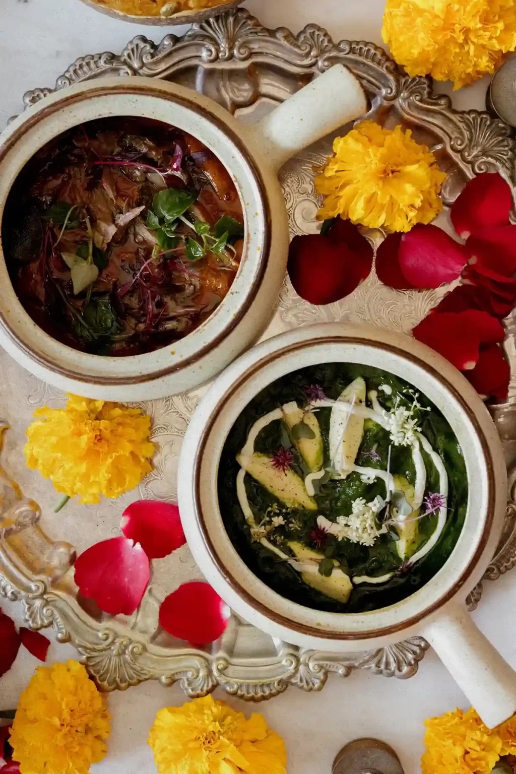 Two curries in bowls surrounded by flowers at Red Gunpowder