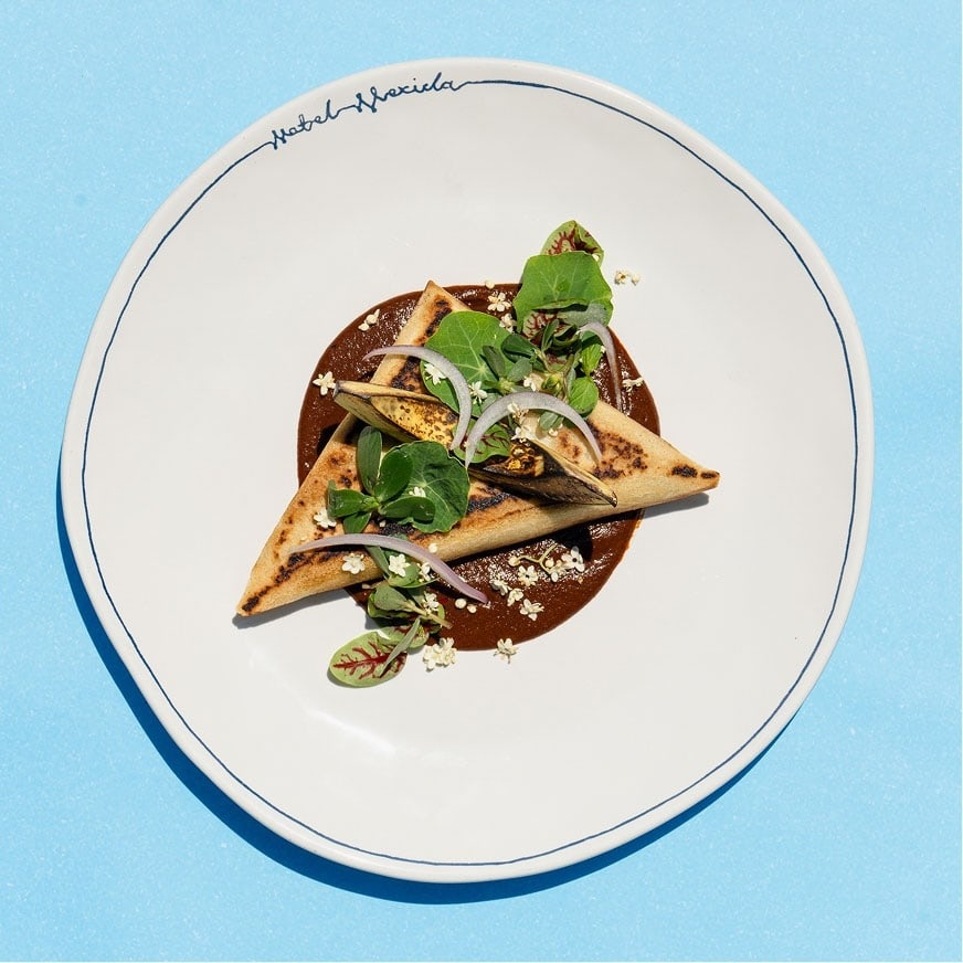 A tostada with herbs and sauce on a white plate at Motel Mexicola