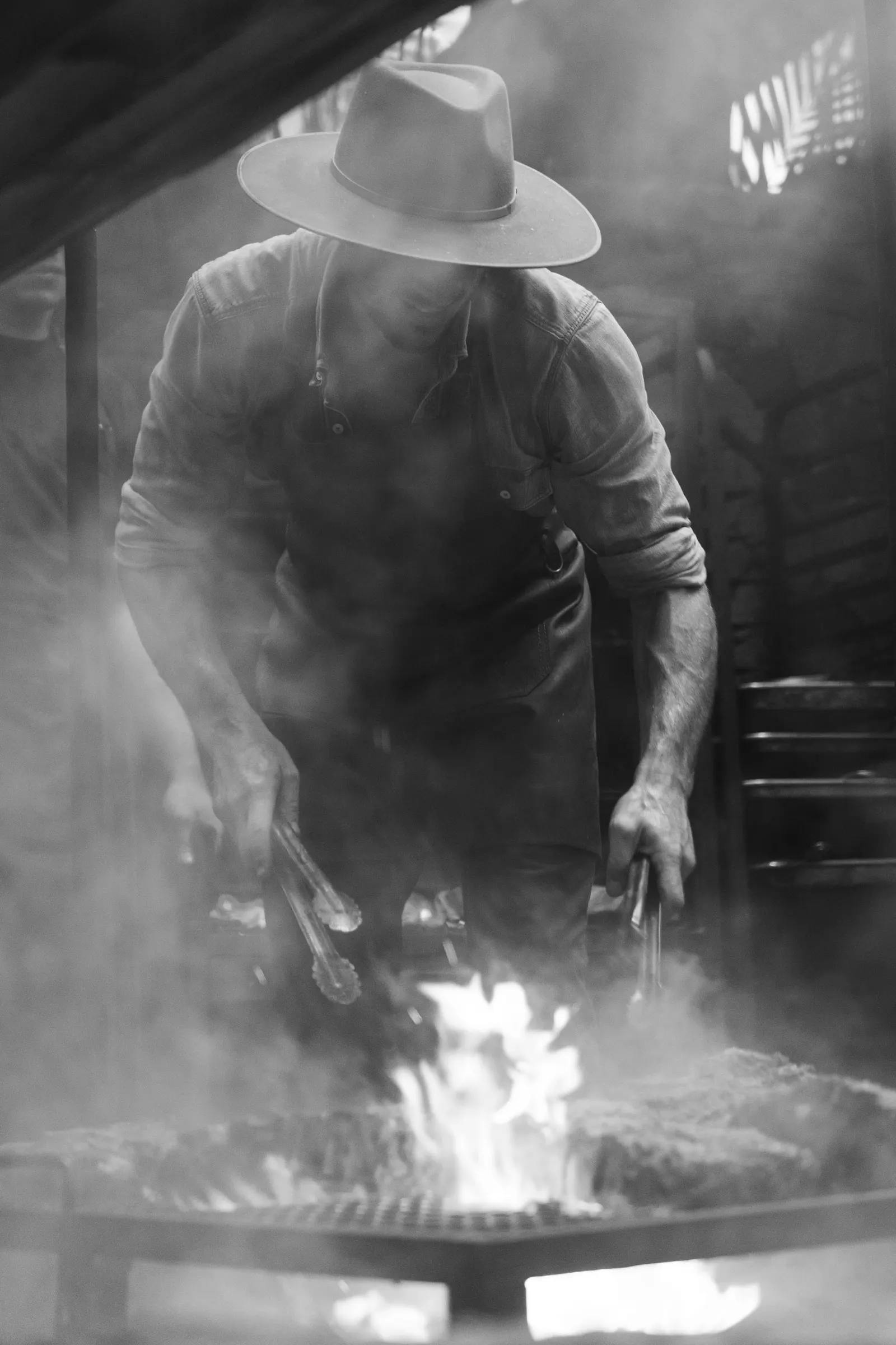 Chef Charly Pretet tending an open wood fire at a Shelter x Terra Firma Dining event