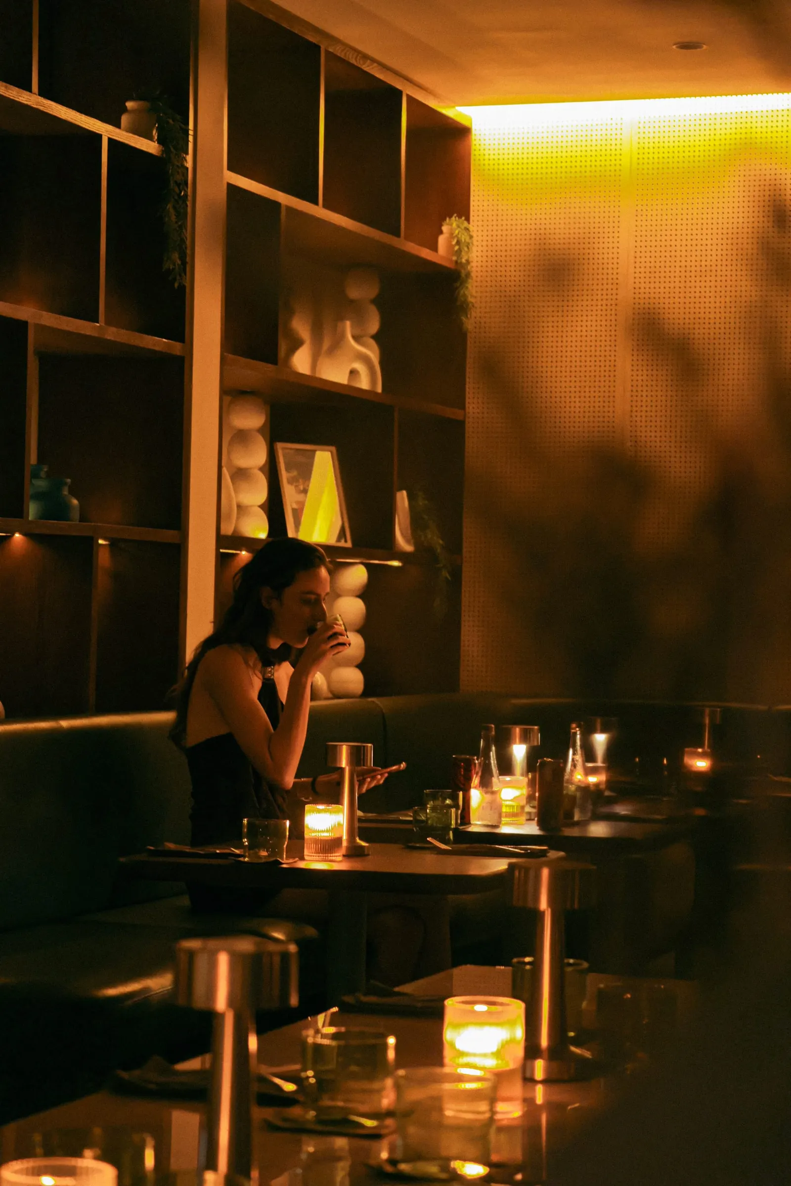 Dimly lit dining room at nüde Berawa's new Canggu dinner service, with candlelit tables and projector visuals on the wall.